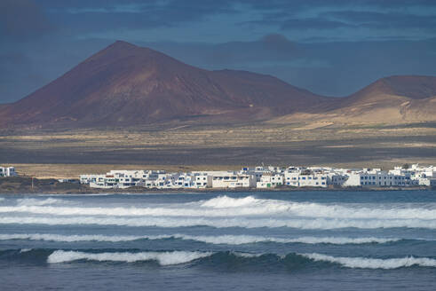 Spain, Canary Islands, Caleta de Famara, Coastal village with mountain in background - WGF01467