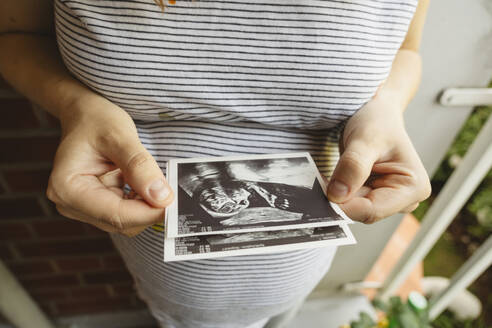 Schwangere Frau hält Ultraschallbild zu Hause - IHF01480