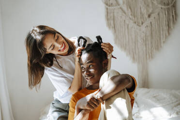 Happy girlfriend playing with boyfriend's hair at home - NLAF00061