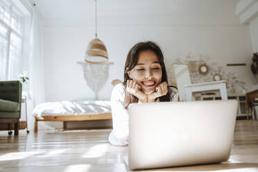 Freelancer working with laptop lying on floor at home - NLAF00078