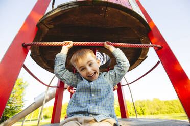Happy boy sitting having fun in playground - IHF01506