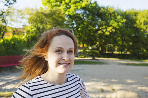 Lächelnde Frau mit braunem Haar auf einem Spielplatz - IHF01507