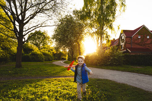 Happy boy running with toy airplane at sunset - IHF01510