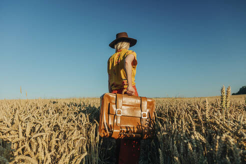 Frau mit Hut und Koffer in einem Weizenfeld - VSNF01234