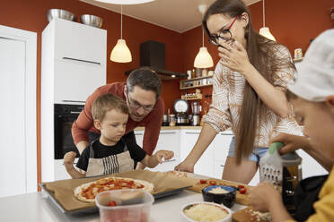 Glückliche Familie, die zu Hause gemeinsam Pizza zubereitet - SANF00122