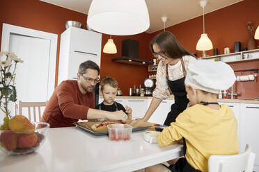 Glückliche Familie bei der Zubereitung einer Pizza in der Küche zu Hause - SANF00124