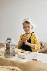 Junge mit Kochmütze bei der Zubereitung von Speisen zu Hause - SANF00126