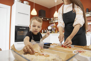 Junge bereitet mit seiner Mutter zu Hause eine Pizza zu - SANF00133