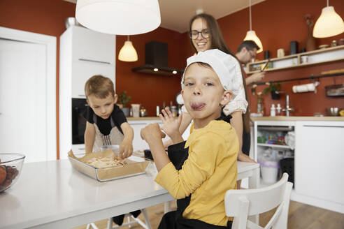 Boy sticking out tongue and doing mischief with family at home - SANF00135