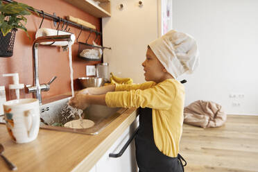 Lächelnder Junge beim Händewaschen in der Küche zu Hause - SANF00136