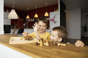 Glücklicher Junge spielt Schach mit seinem Bruder zu Hause - SANF00144