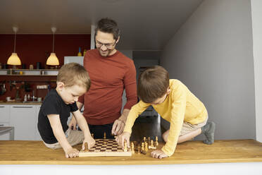Vater unterrichtet seine Söhne zu Hause im Schach - SANF00145