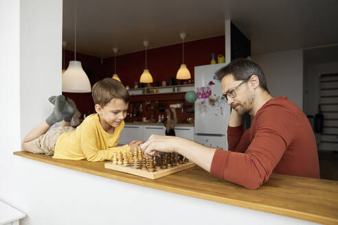 Nachdenklicher Vater spielt mit seinem Sohn zu Hause Schach - SANF00146