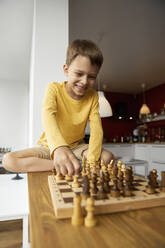 Glücklicher Junge spielt Schach zu Hause - SANF00150