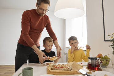 Vater serviert seinem Sohn zu Hause eine Pizza - SANF00160