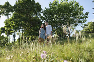 Man and woman standing on grass at sunny day - ASGF03885