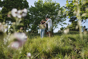 Mann und Frau diskutieren über eine Landkarte, die auf einer Wiese im Park steht - ASGF03890