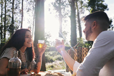 Happy couple having drinks in forest at sunny day - ASGF03903