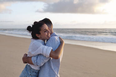 Happy woman embracing boyfriend at beach - ASGF03951