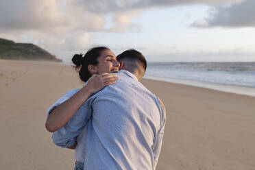 Happy woman embracing boyfriend at beach - ASGF03952