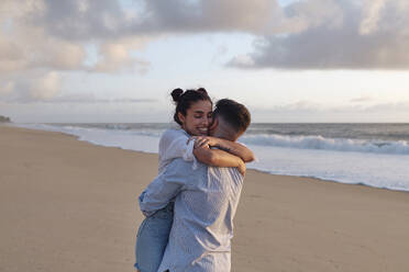 Young man embracing woman at beach - ASGF03953