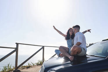 Man sitting with girlfriend on car hood - ASGF03969