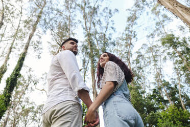 Boyfriend and girlfriend holding hands exploring forest - ASGF03985