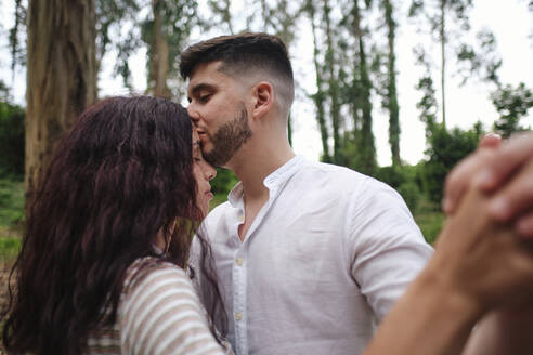 Mann küsst Freundin mit geschlossenen Augen im Wald - ASGF03999