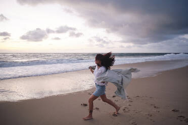 Carefree woman running on sand at beach - ASGF04023