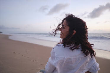 Happy woman with tousled hair at beach - ASGF04025