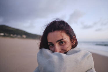 Woman wrapped in blanket at beach - ASGF04029