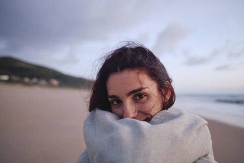 Woman wrapped in blanket at beach - ASGF04029