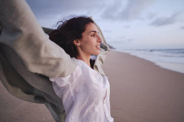 Frau mit erhobenen Armen am Meer stehend am Strand - ASGF04033