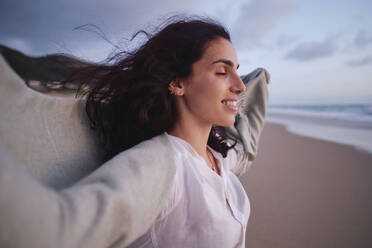 Smiling woman with eyes closed at beach - ASGF04035