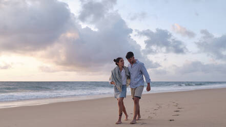 Boyfriend and girlfriend strolling together on sand at beach - ASGF04062