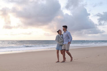 Woman talking to boyfriend walking on sand at beach - ASGF04064