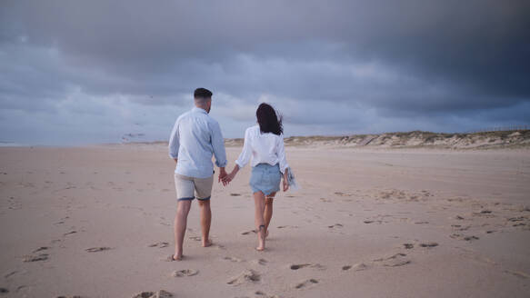 Paar läuft händchenhaltend auf Sand am Strand - ASGF04074
