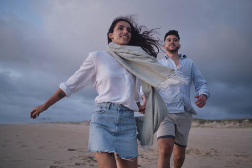 Young girlfriend running with boyfriend at beach - ASGF04078