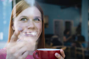 Lächelnde Frau mit Kaffeetasse in einem Cafe - AMWF01636