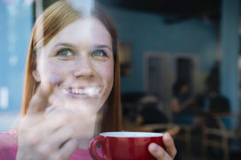 Smiling woman holding coffee cup at cafe - AMWF01636