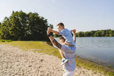 Vater trägt Sohn auf der Schulter am See - IHF01518