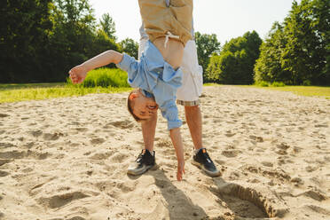 Father carrying son upside down on field - IHF01524