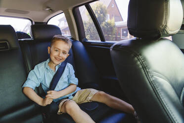 Smiling boy wearing seat belt in car - IHF01531