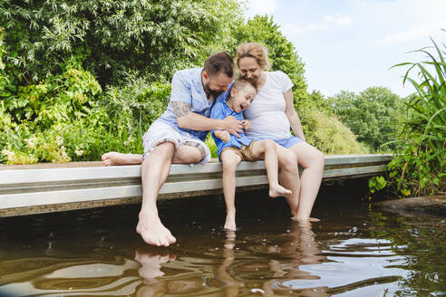 Eltern verbringen ihre Freizeit mit ihrem Sohn auf einem Steg über den See - IHF01544