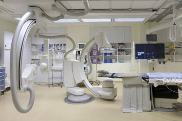 Ein modernes Krankenhauszimmer, ein großes tragbares mobiles Scangerät mit gebogenen Armen, ein mobiler Scanner und eine Krankenhausliege oder ein Bett. - MINF16622