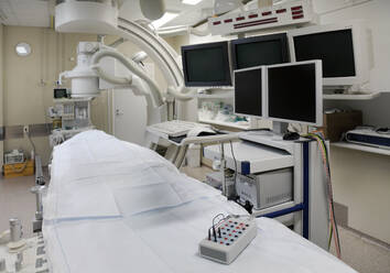 Ein modernes Krankenhauszimmer, ein großes tragbares Scangerät mit gebogenen Armen und mehreren Bildschirmen für die medizinische Bildgebung. - MINF16625