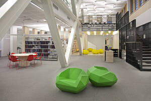 A healthcare college library with open spaces, green chairs and book stacks. A modern light and airy building. - MINF16631