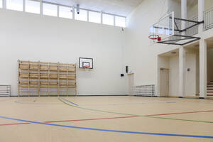 Indoor-Basketballplatz in einer Schule: Holzboden und markiertes Spielfeld, ein Korb und ein Backboard. - MINF16637