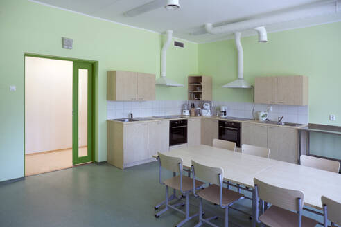 A modern school, a kitchen with fitted cupboards and ovens, a long table and chairs. - MINF16645