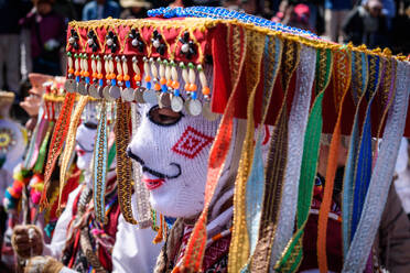 Cusco, a cultural fiesta, people dressed in traditional colourful costumes with masks and hats, brightly coloured streamers. - MINF16679